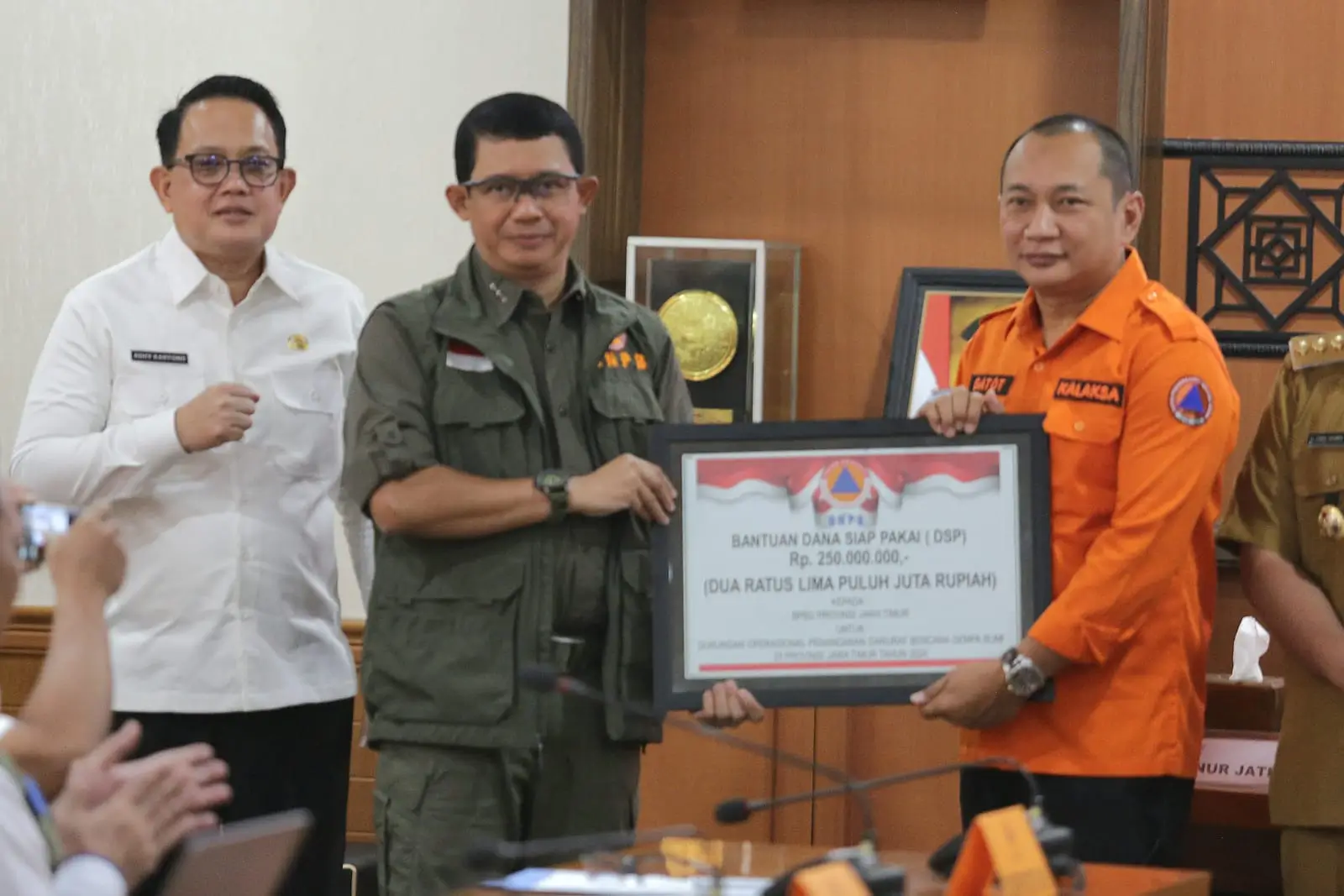 Kepala BNPB Letjen TNI Suharyanto, S.Sos., M.M (kemeja dan rompi hijau) saat memberikan simbolis dukungan bantuan penanganan darurat kepada pemerintah daerah, pada Rapat Koordinasi Penanganan Darurat Gempa di Kantor Bupati Gresik, Jawa Timur pada Senin (25/3).